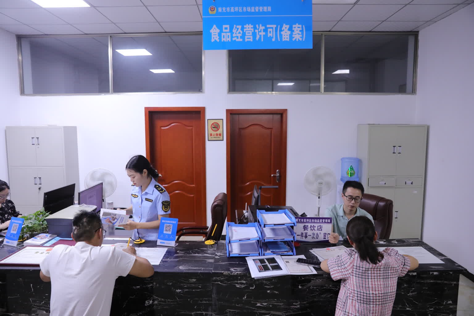 在高坪区白塔市场监管所,工作人员正在为申办人办理食品经营许可证。高坪区融媒体中心供图
