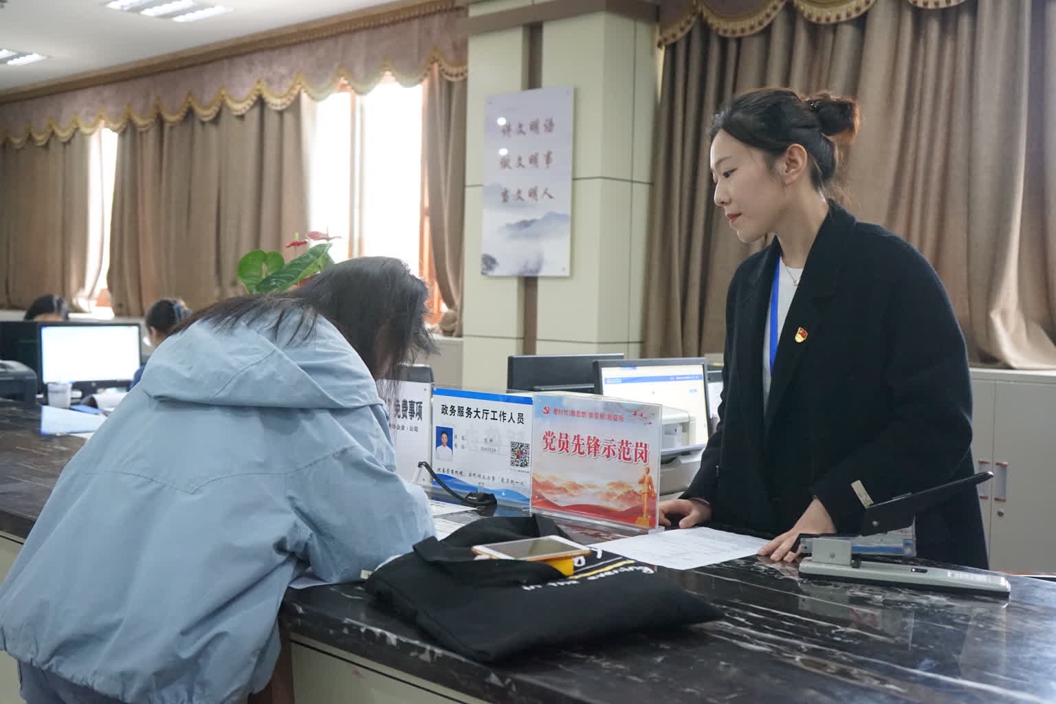 在高坪区行政审批办事大厅,工作人员正在指导申办人填写表格。高坪区融媒体中心供图